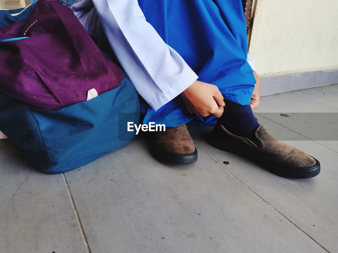 Low section of woman wearing shoe on floor