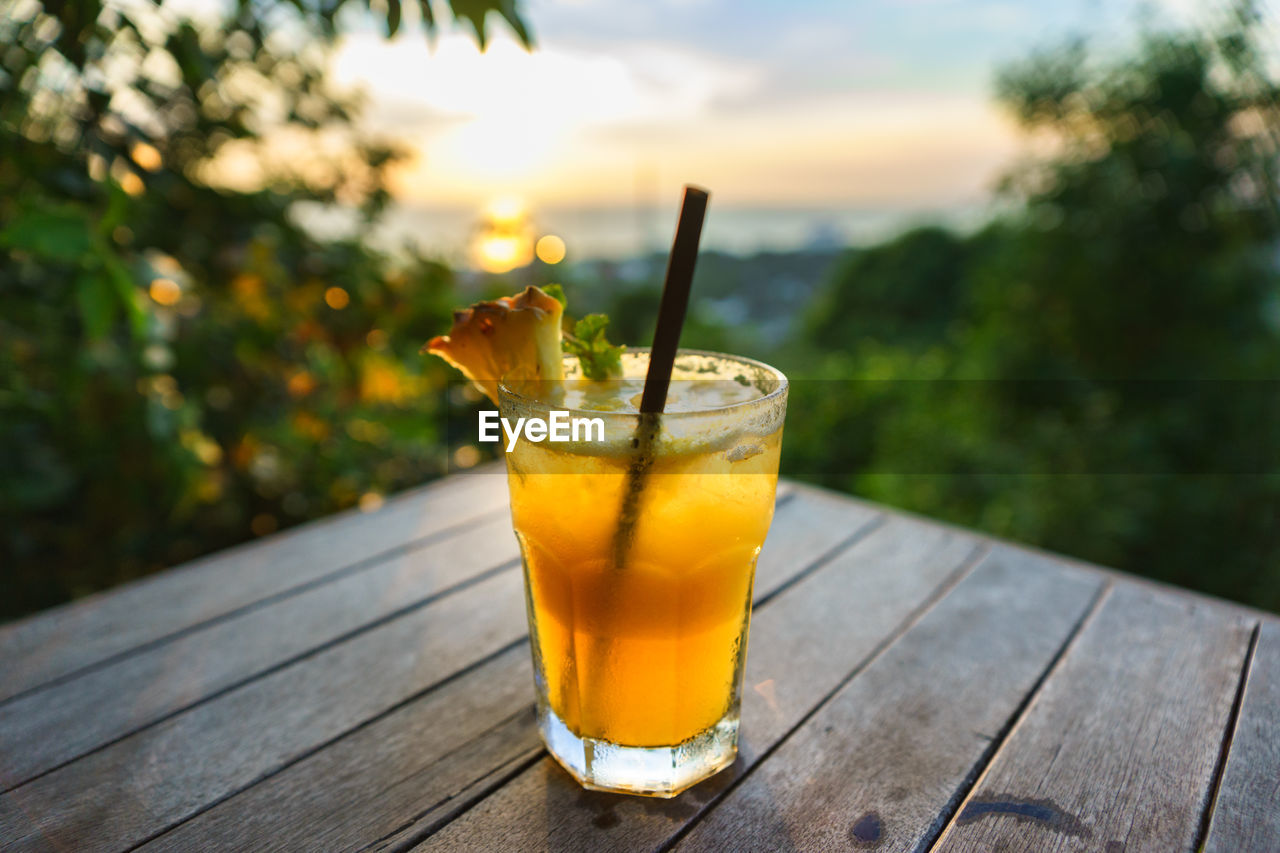 Close-up of drink on table during sunset