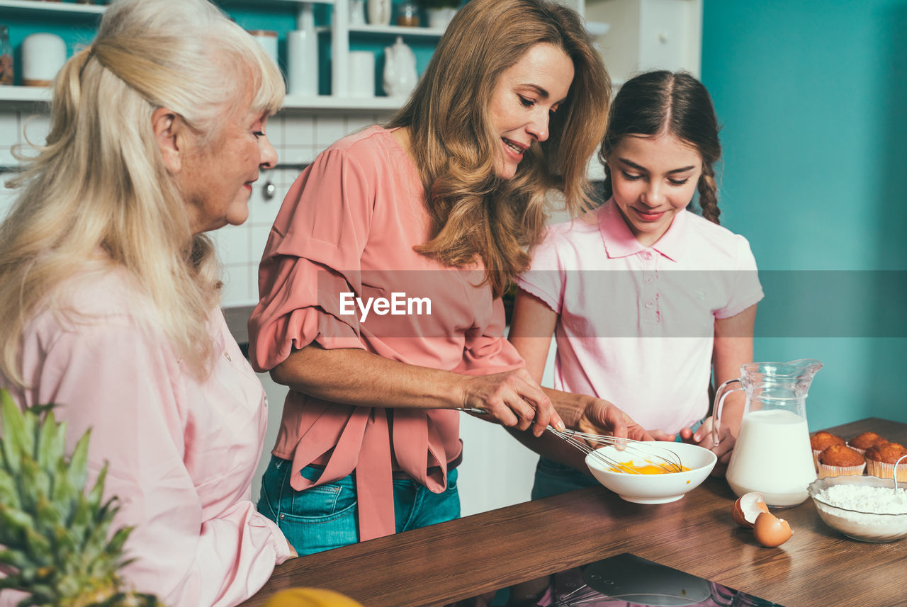 Cheerful daughter with parents preparing food at kitchen