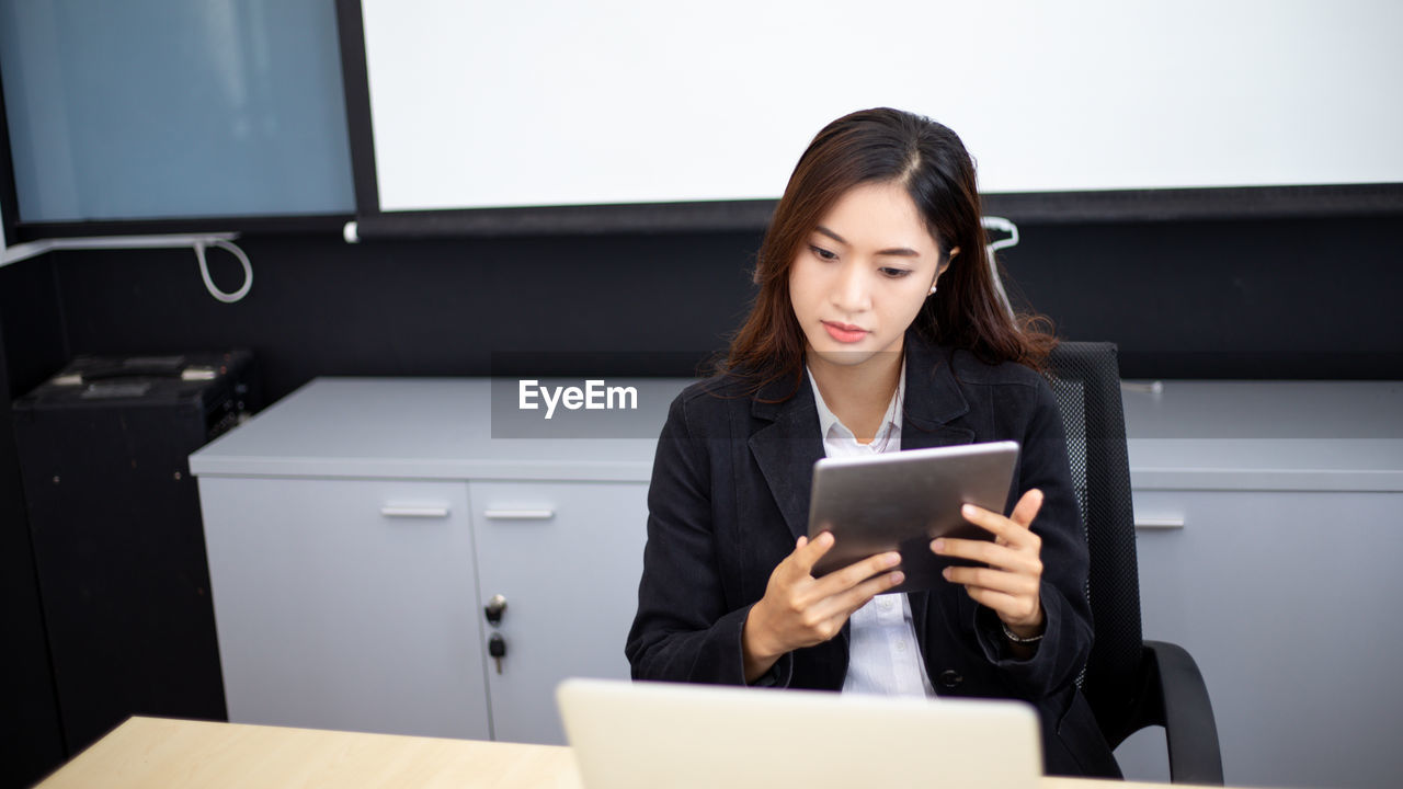 young woman using digital tablet while sitting on table