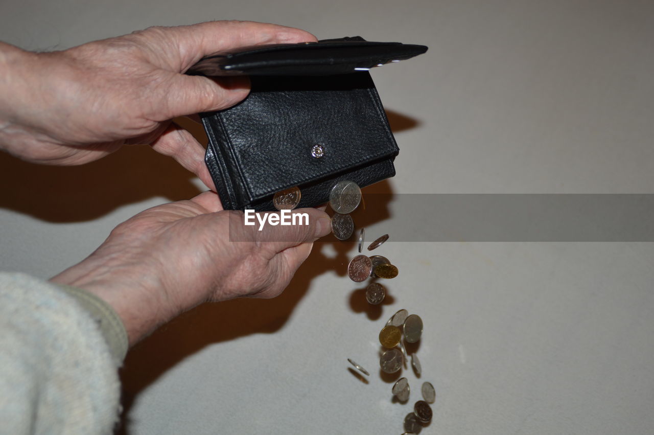Cropped image of hands dropping coins out from wallet