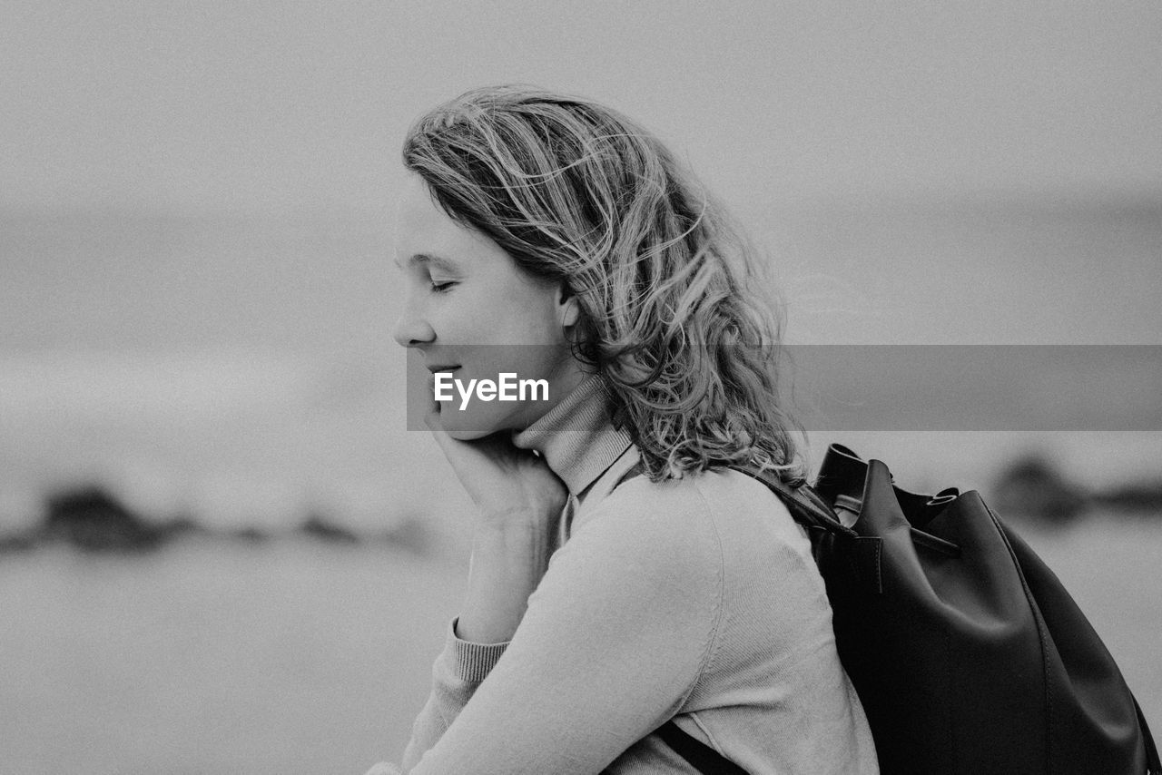 PORTRAIT OF WOMAN STANDING AT BEACH