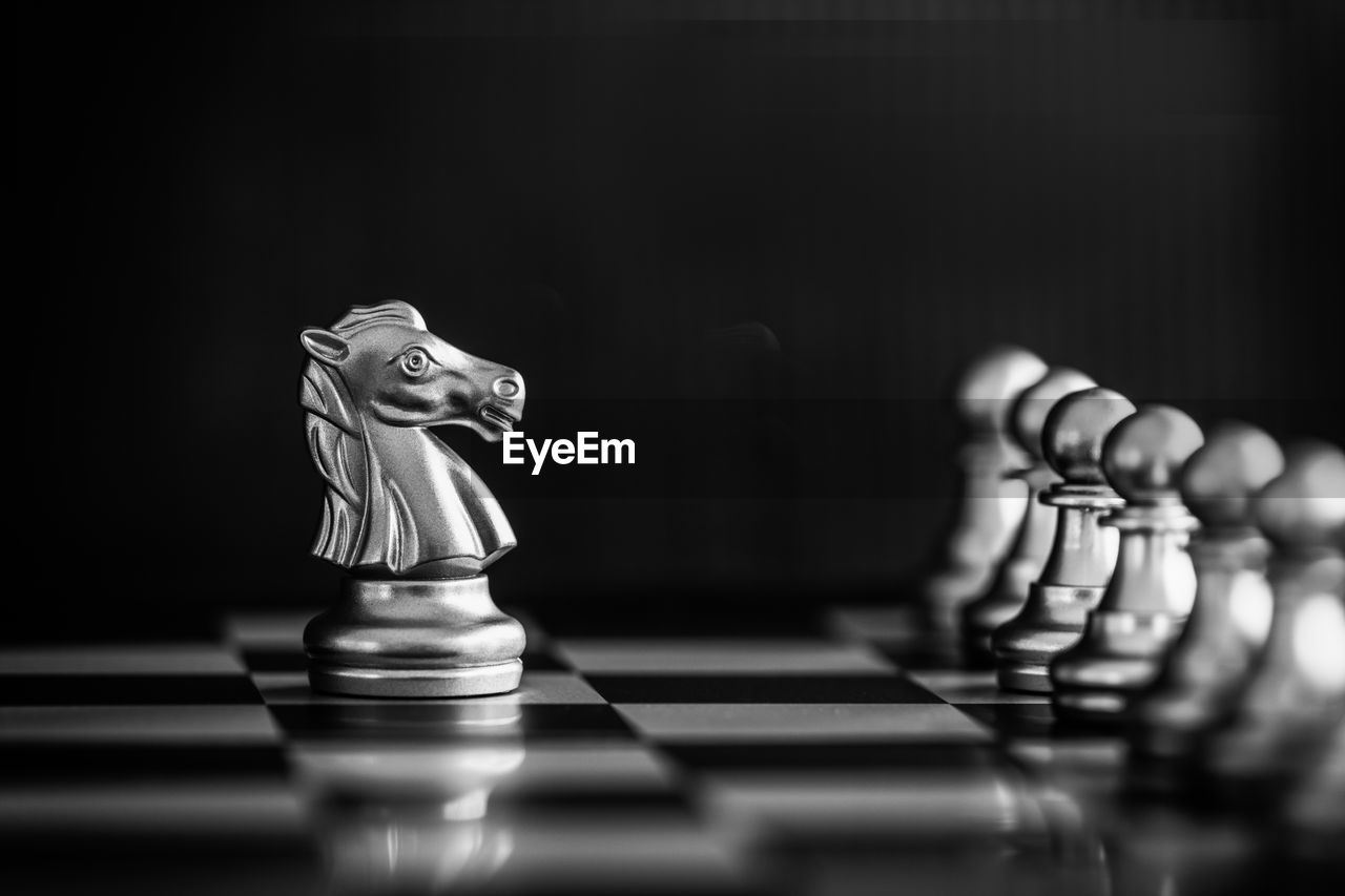 Close-up of chess pieces on board against black background