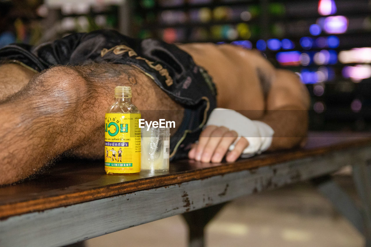 MIDSECTION OF MAN LYING DOWN ON BOTTLES