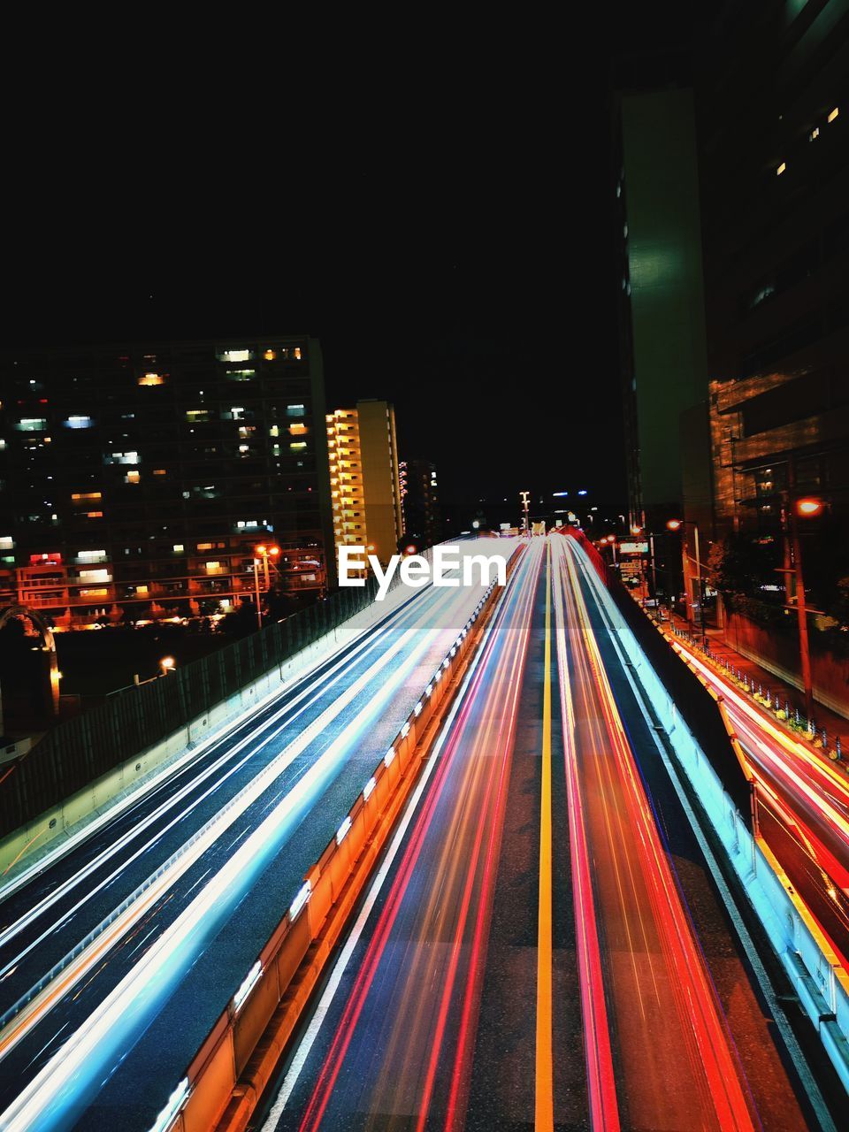 Light trails on city street by buildings at night