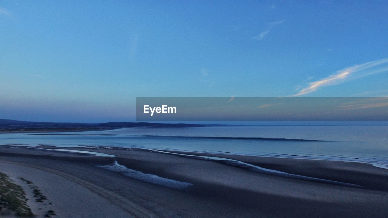 Scenic view of beach against blue sky