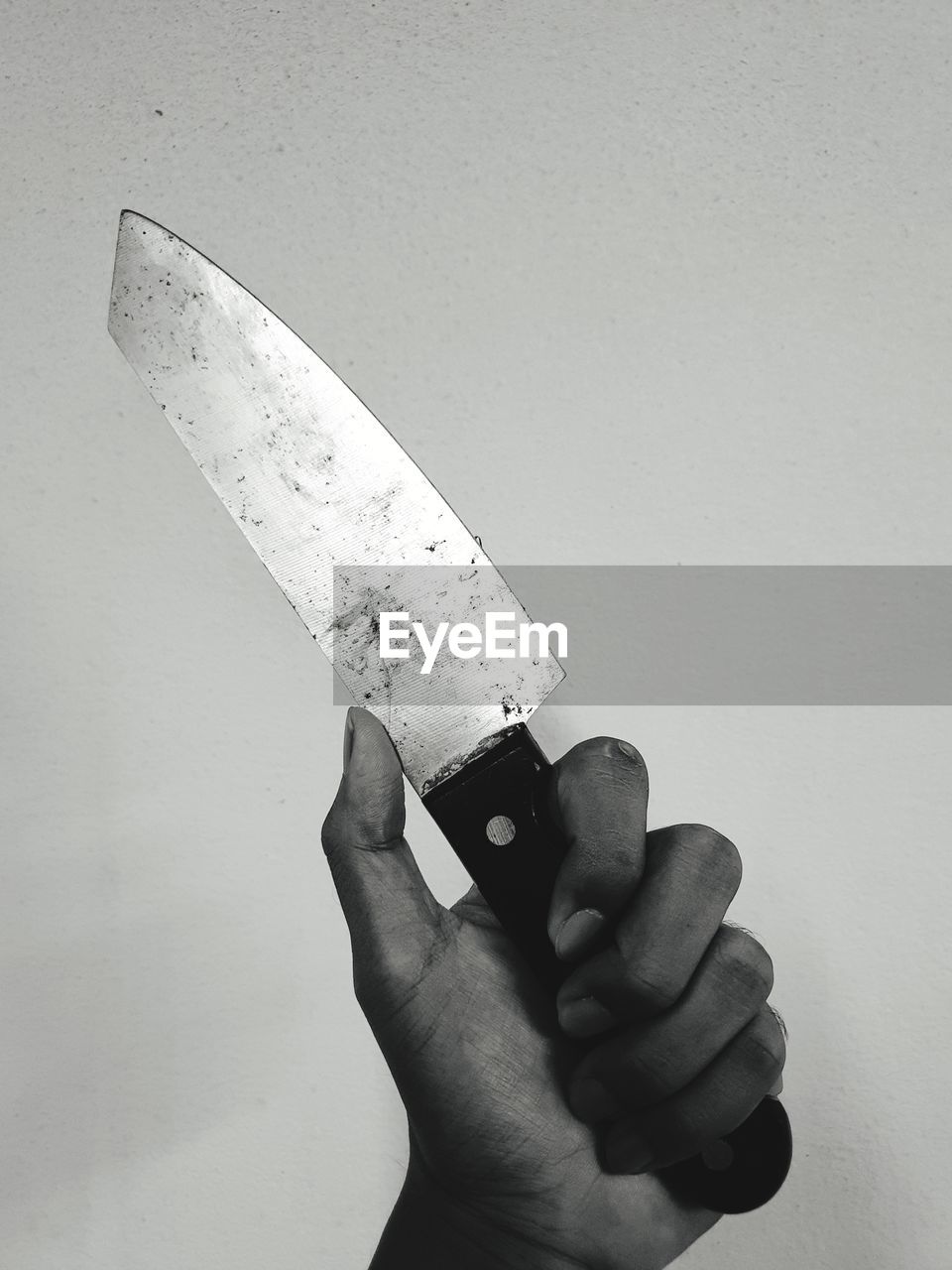 Close-up of hand holding knife against white background