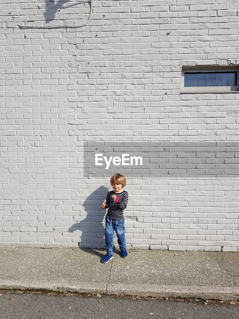 Full length of boy standing against brick wall