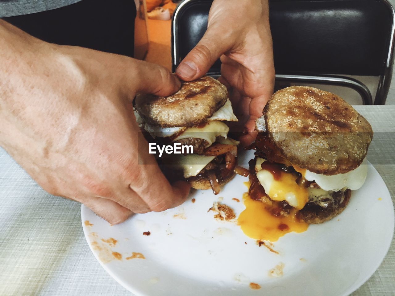 Cropped hand of man holding burger at table