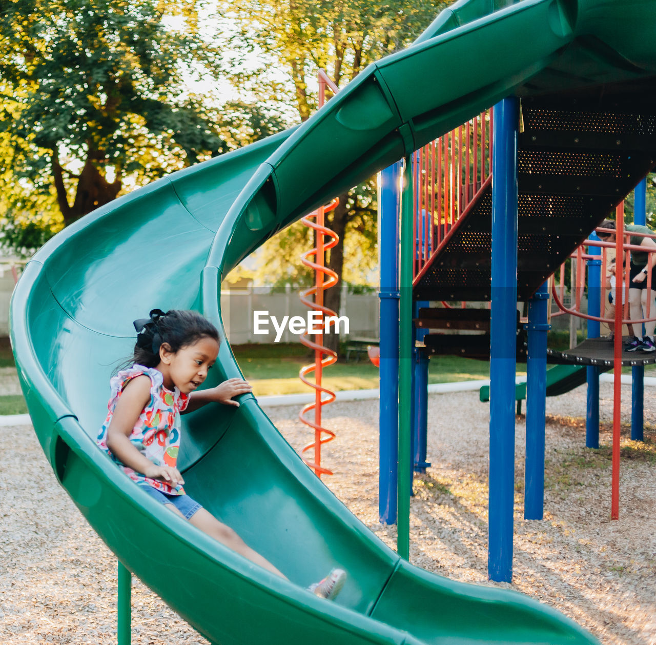 Diverse mixed race pre school girl outdoors during summer having fun at playground park 