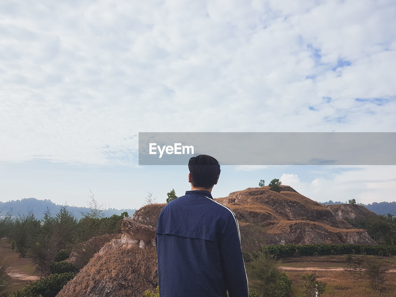 Rear view of man looking at mountains against sky