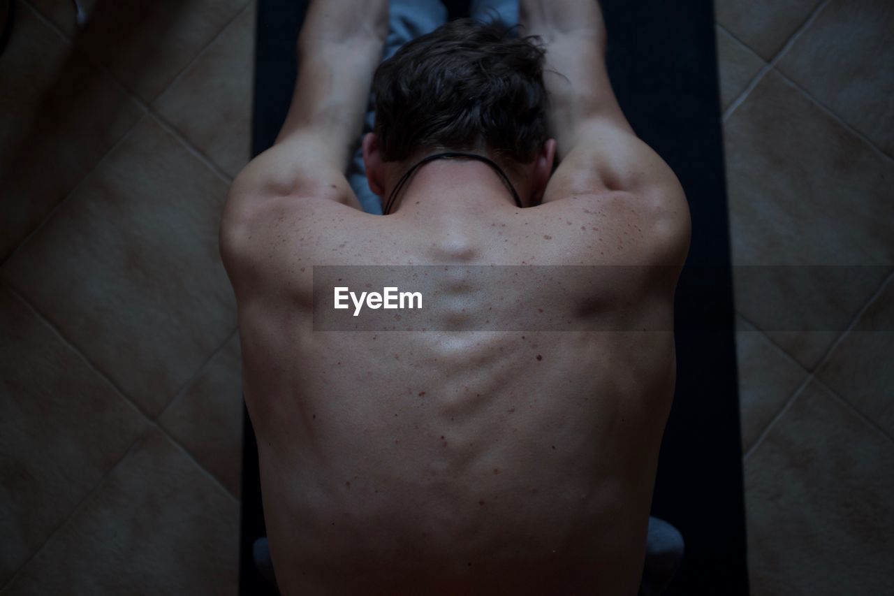 Directly above shot of shirtless man stretching at home