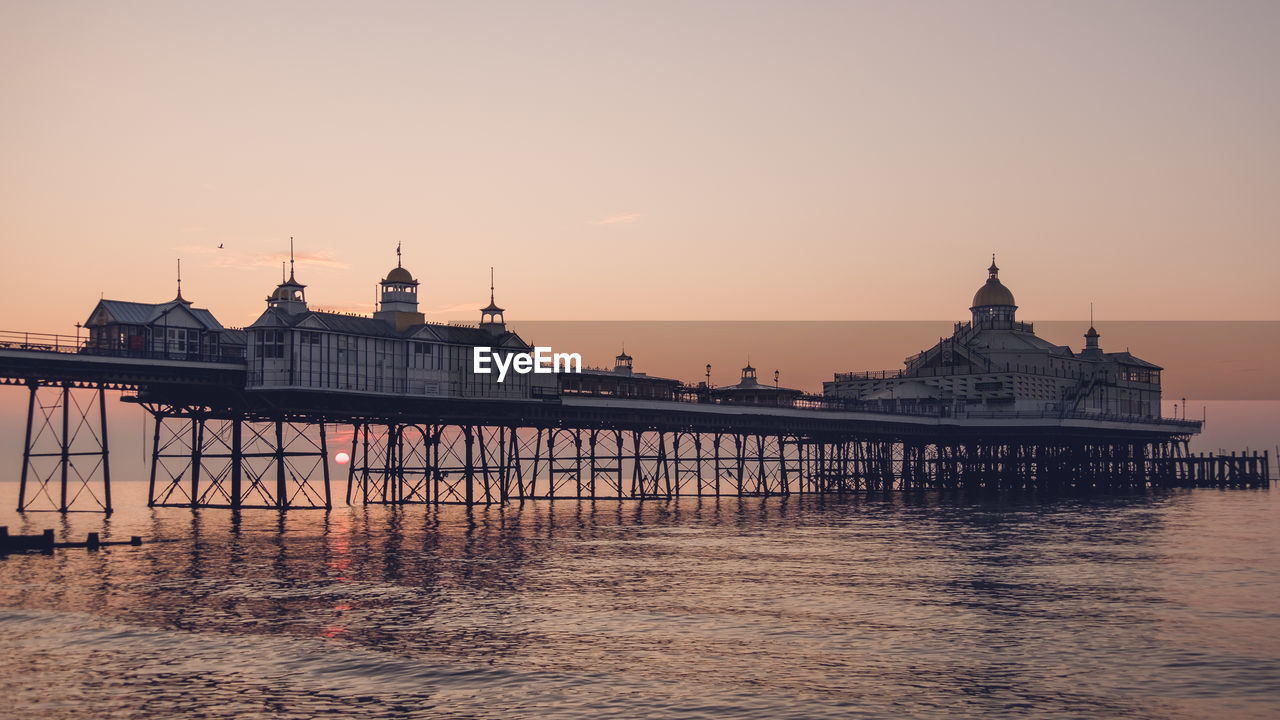 Eastbourne seafront at sunrise with calm sea and clear skies.