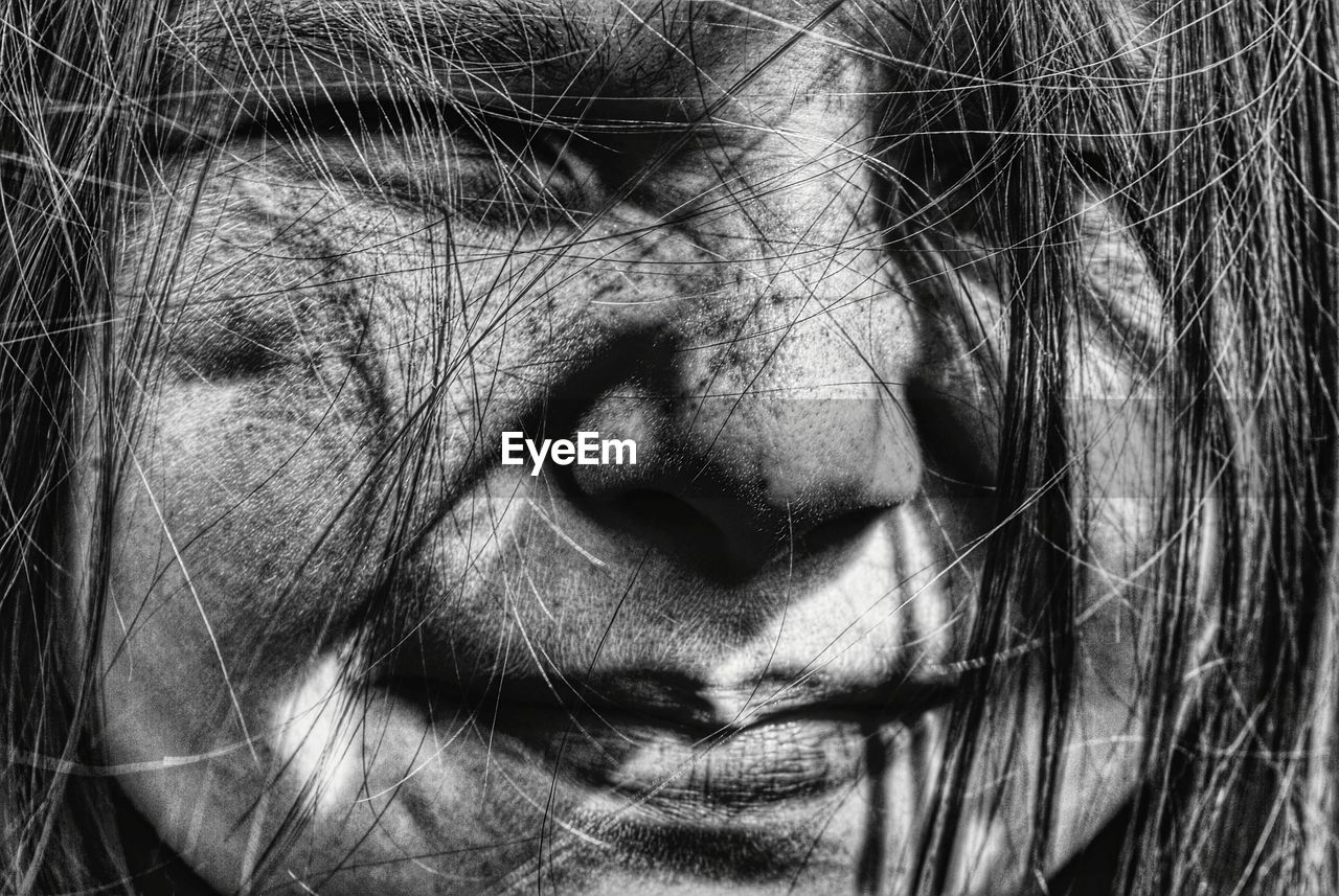 Close-up of girl with hair on face smiling on sunny day