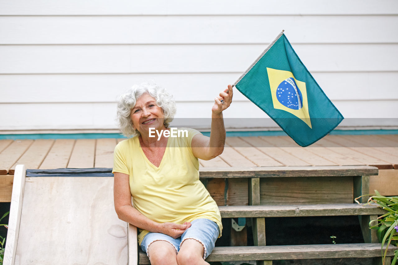 Proud citizen celebrating independence day of brazil. happy old woman with brazilian flag outdoor
