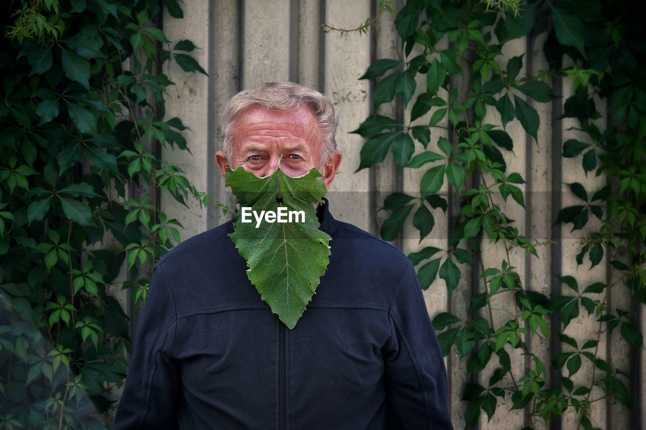 Portrait of senior man with leaf on face
