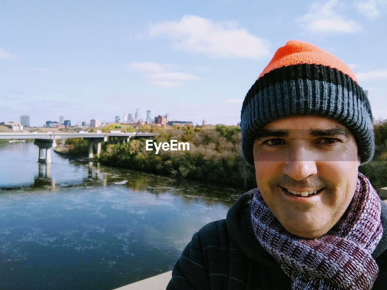 Portrait of smiling mature man wearing knit hat by river