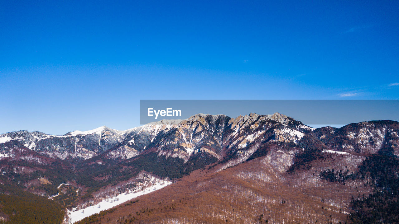 Scenic view of snowcapped mountains against clear blue sky