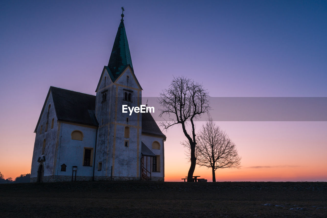 Low angle view of church in field at sunset