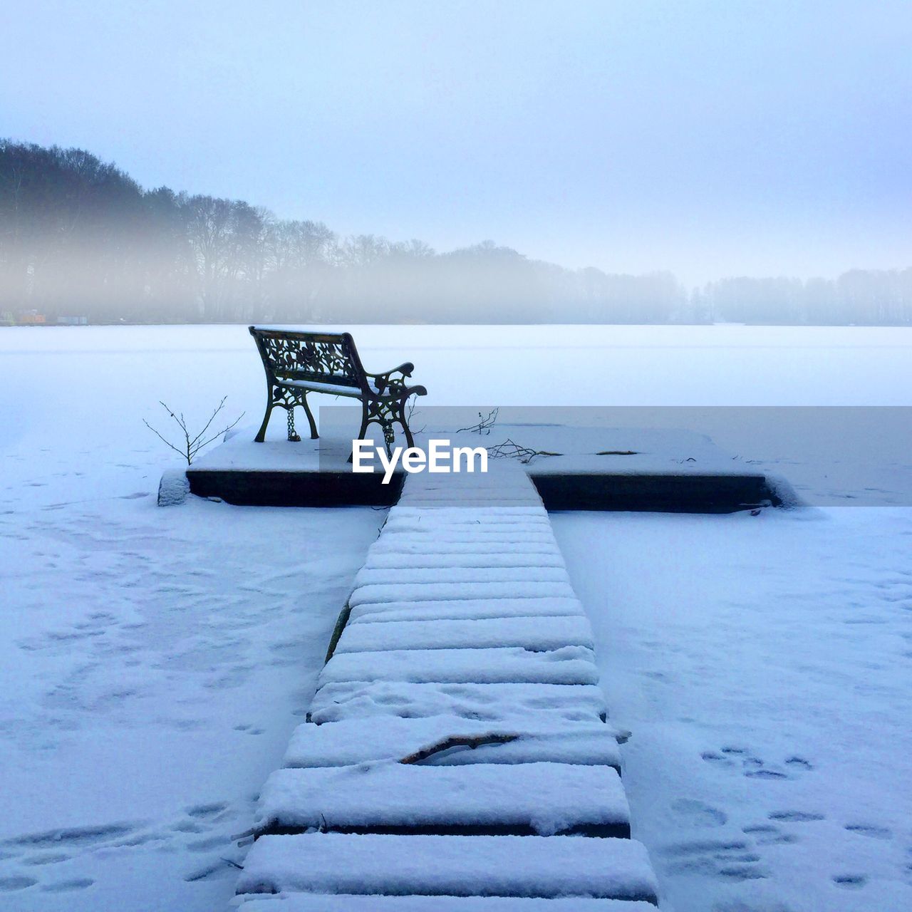 Pier on frozen lake against sky during winter