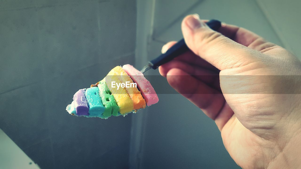 Cropped hand of person holding colorful ice cream