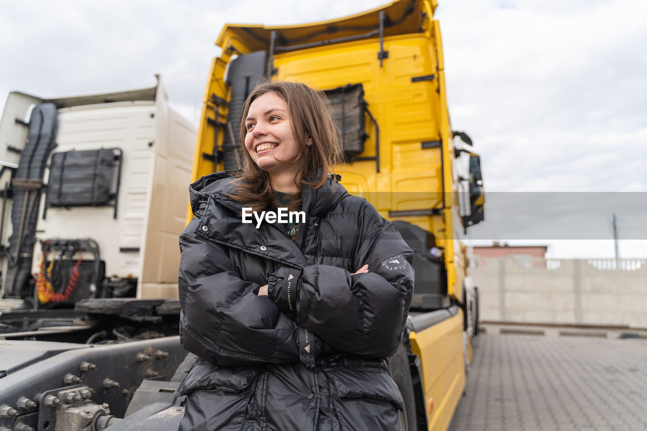 Happy mature woman standing against truck