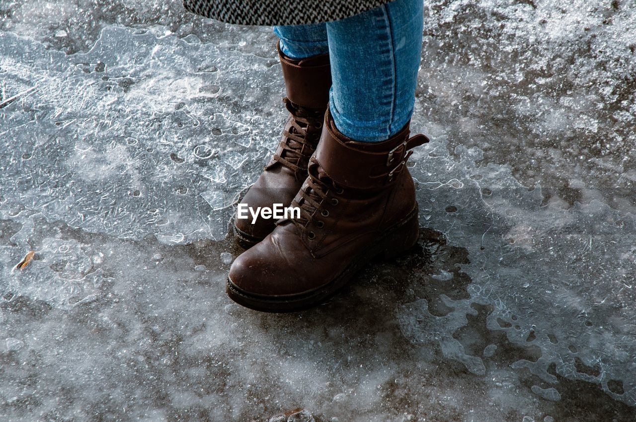 Low section of woman wearing boot while standing on road