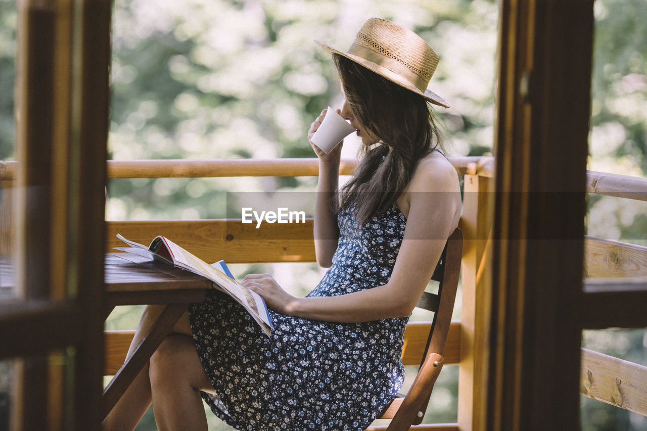 Woman drinking coffee and reading newspapers on balcony