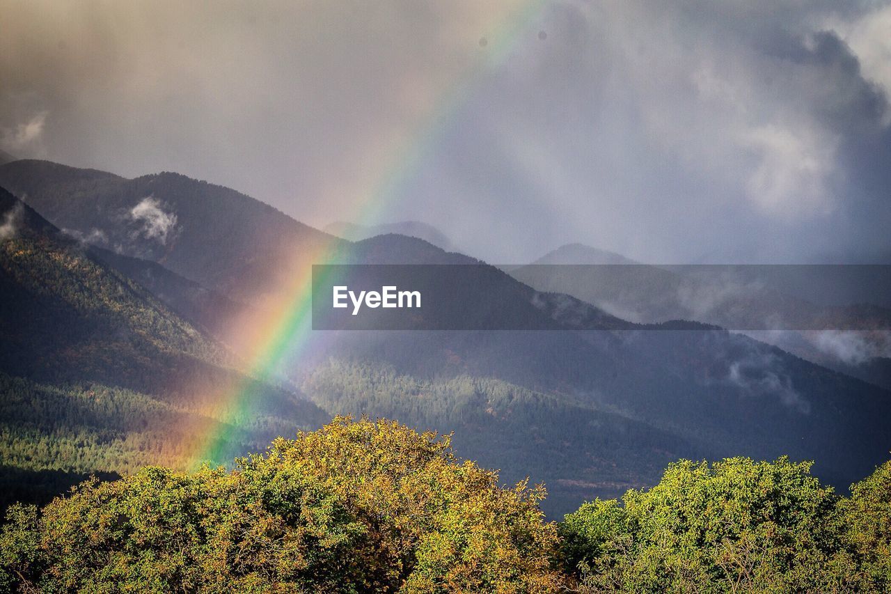 Scenic view of rainbow over mountain against sky