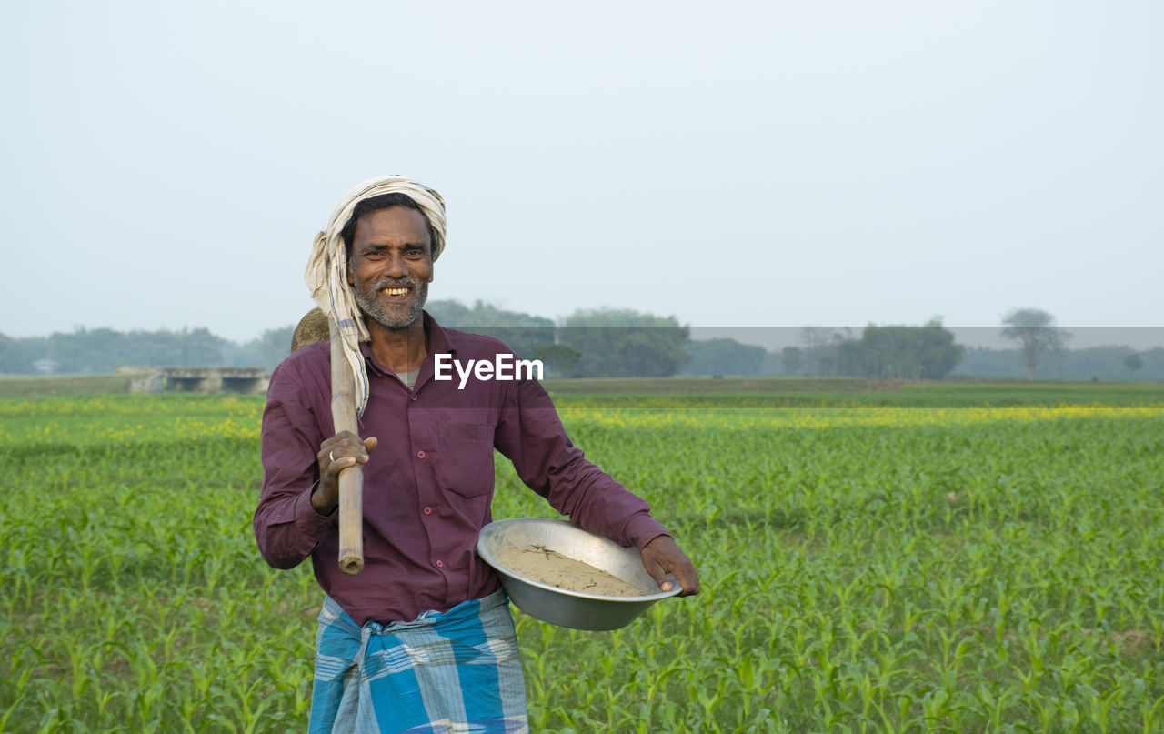 Farmer standing in field with spade and basket