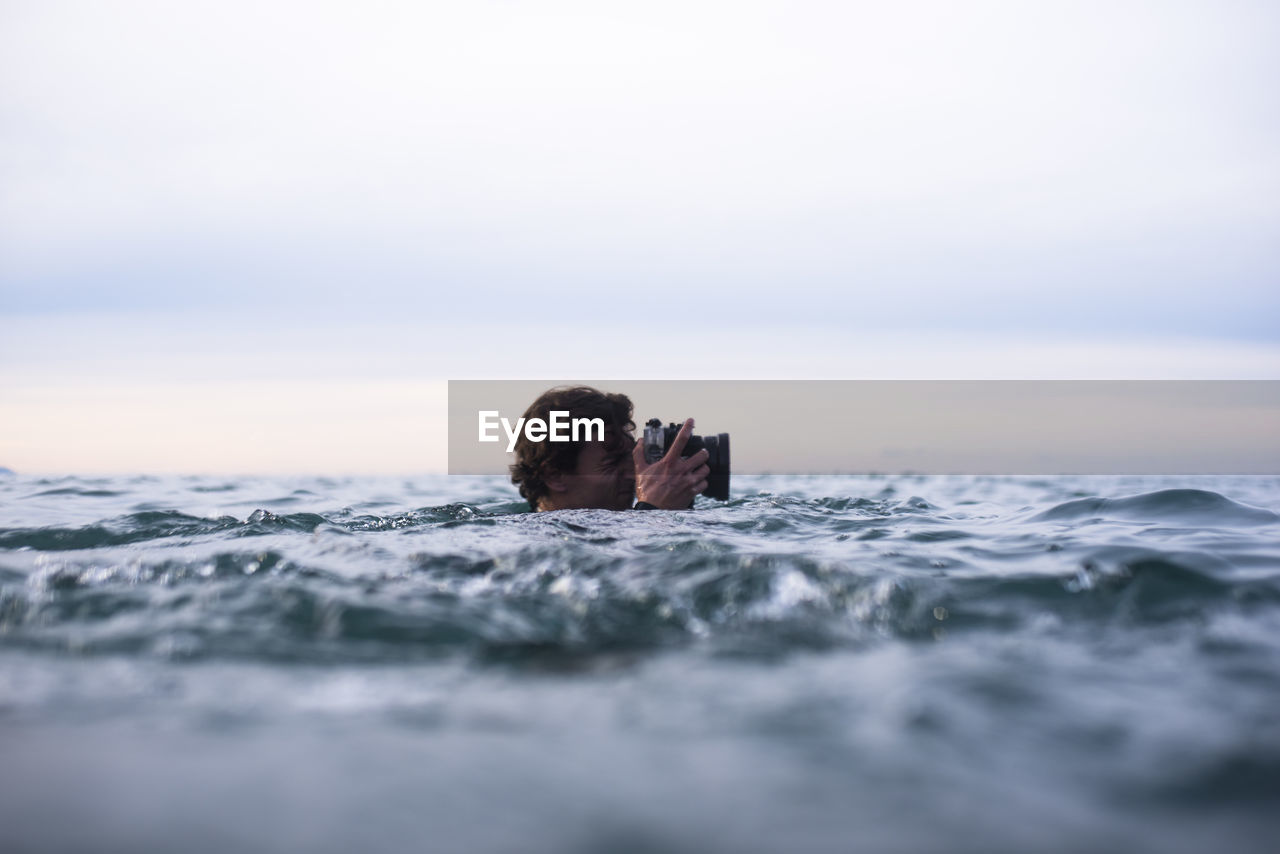 Photographer swimming in the ocean to photograph waves in spain
