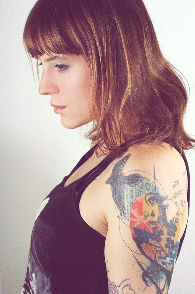 Side view of woman with tattoo standing against wall