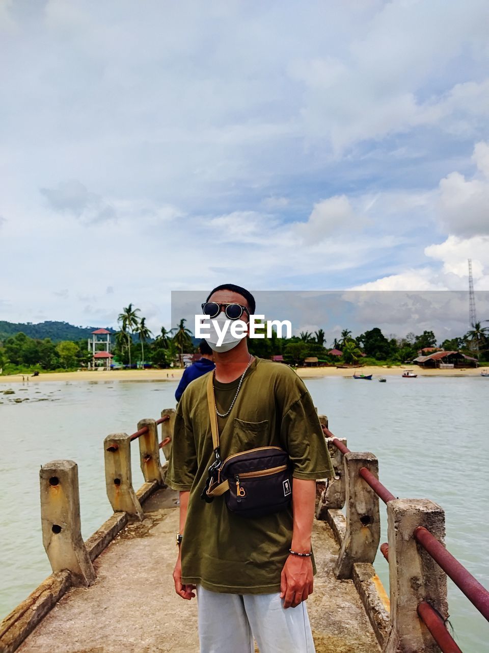 Rear view of man standing by lake against sky