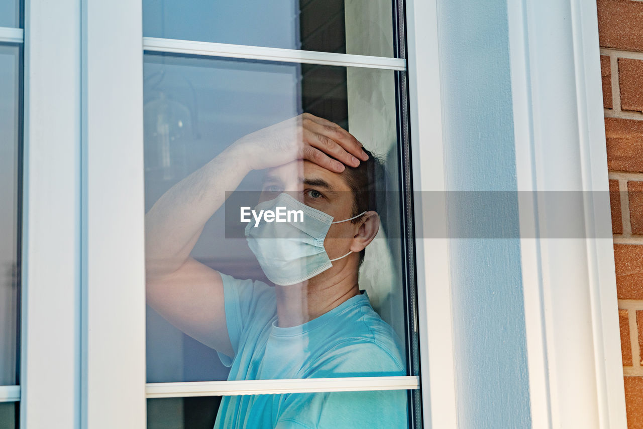 Man wearing mask seen through window