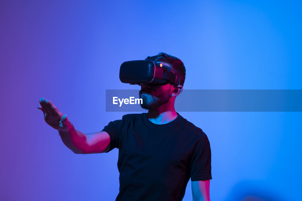 Young man wearing vr against colored background