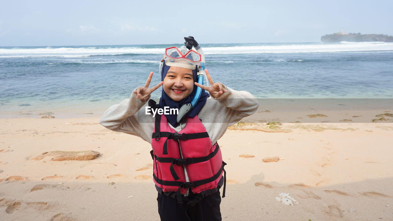 Portrait of woman wearing snorkel standing on beach