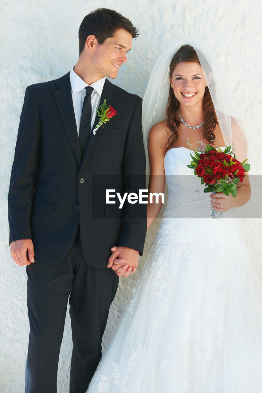 portrait of smiling couple standing in wedding dress