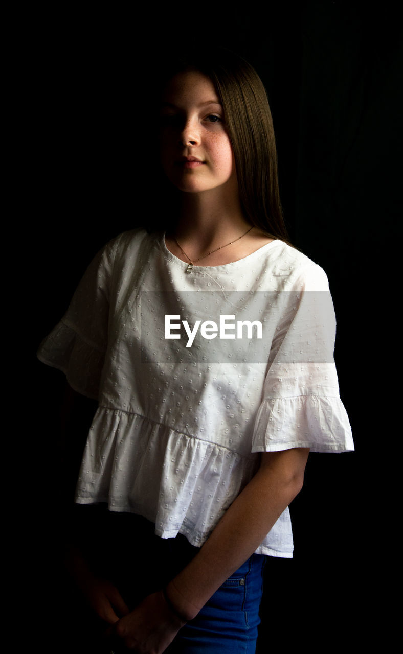 Portrait of a teenage girl over black background