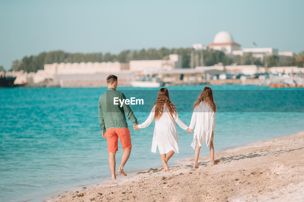 REAR VIEW OF FRIENDS ON BEACH