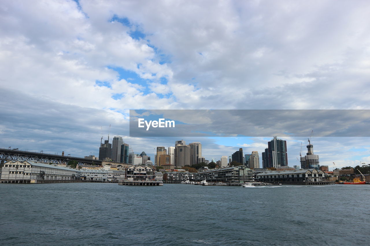 Sea by buildings against sky in city