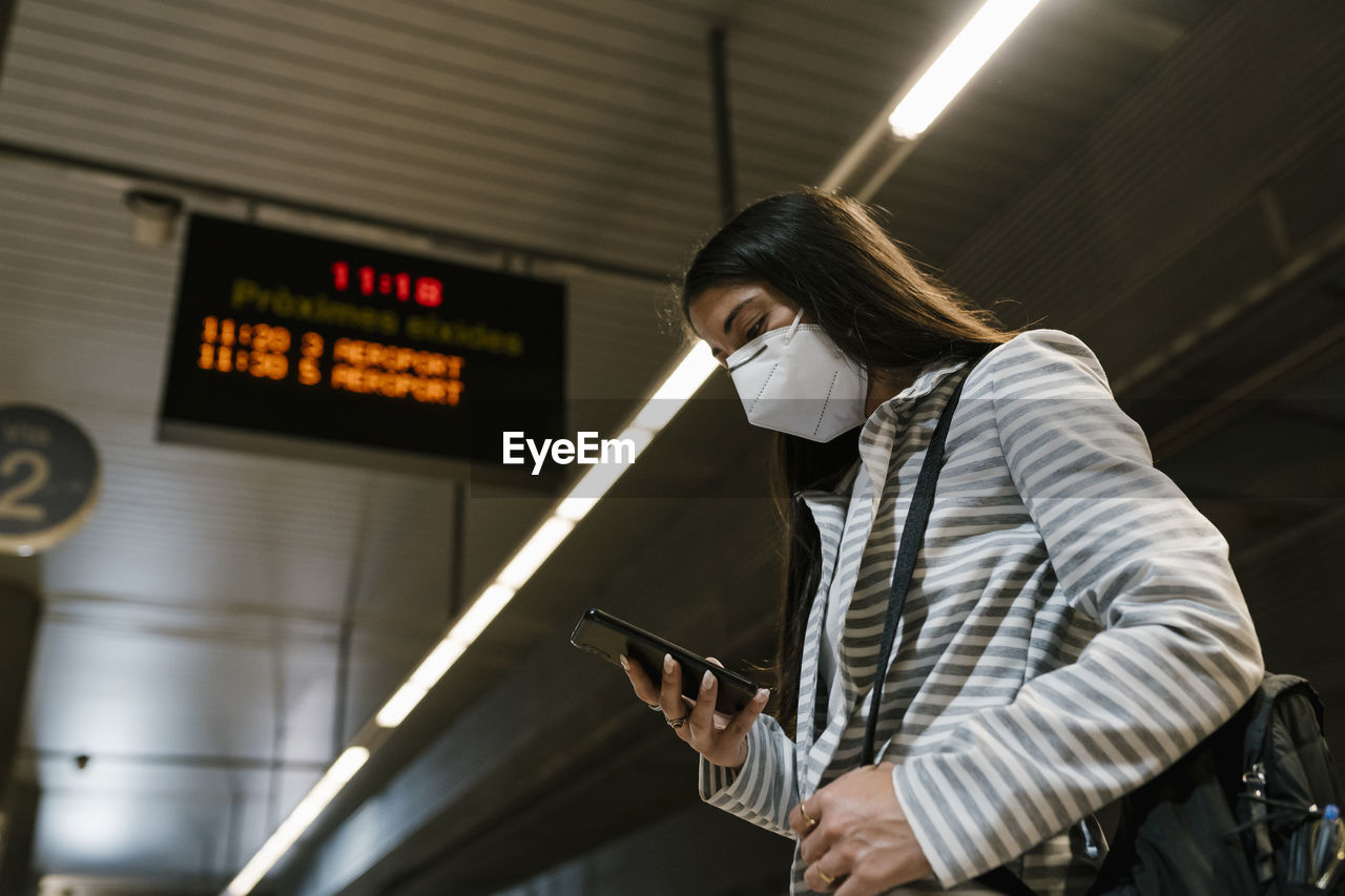 Female passenger using phone while waiting at railroad station