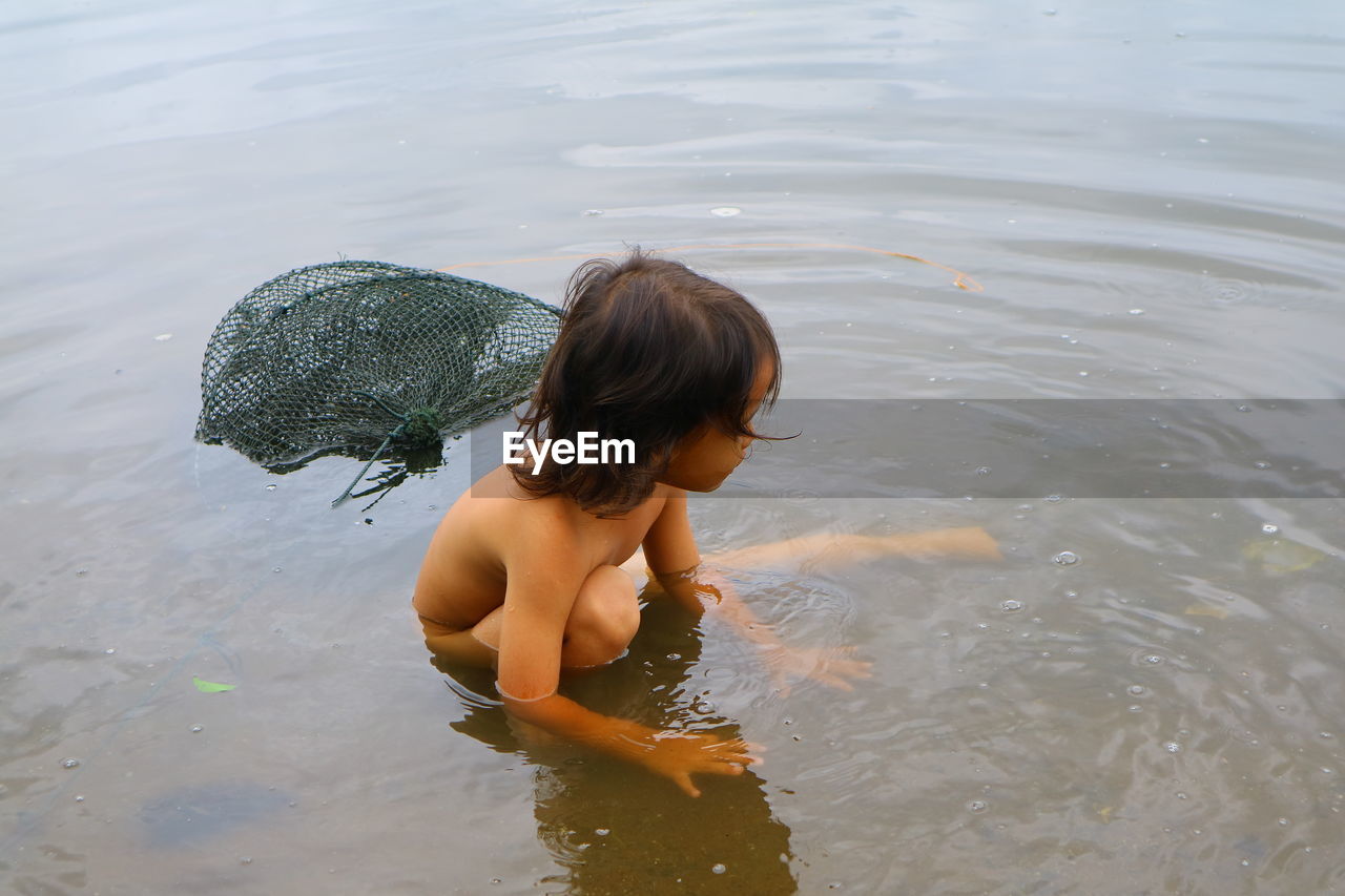 High angle view of shirtless boy in lake