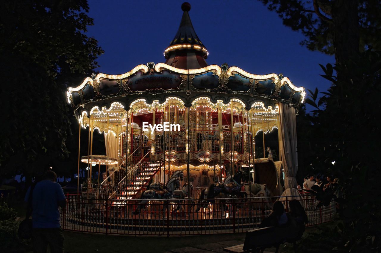 ILLUMINATED CAROUSEL AGAINST SKY AT NIGHT