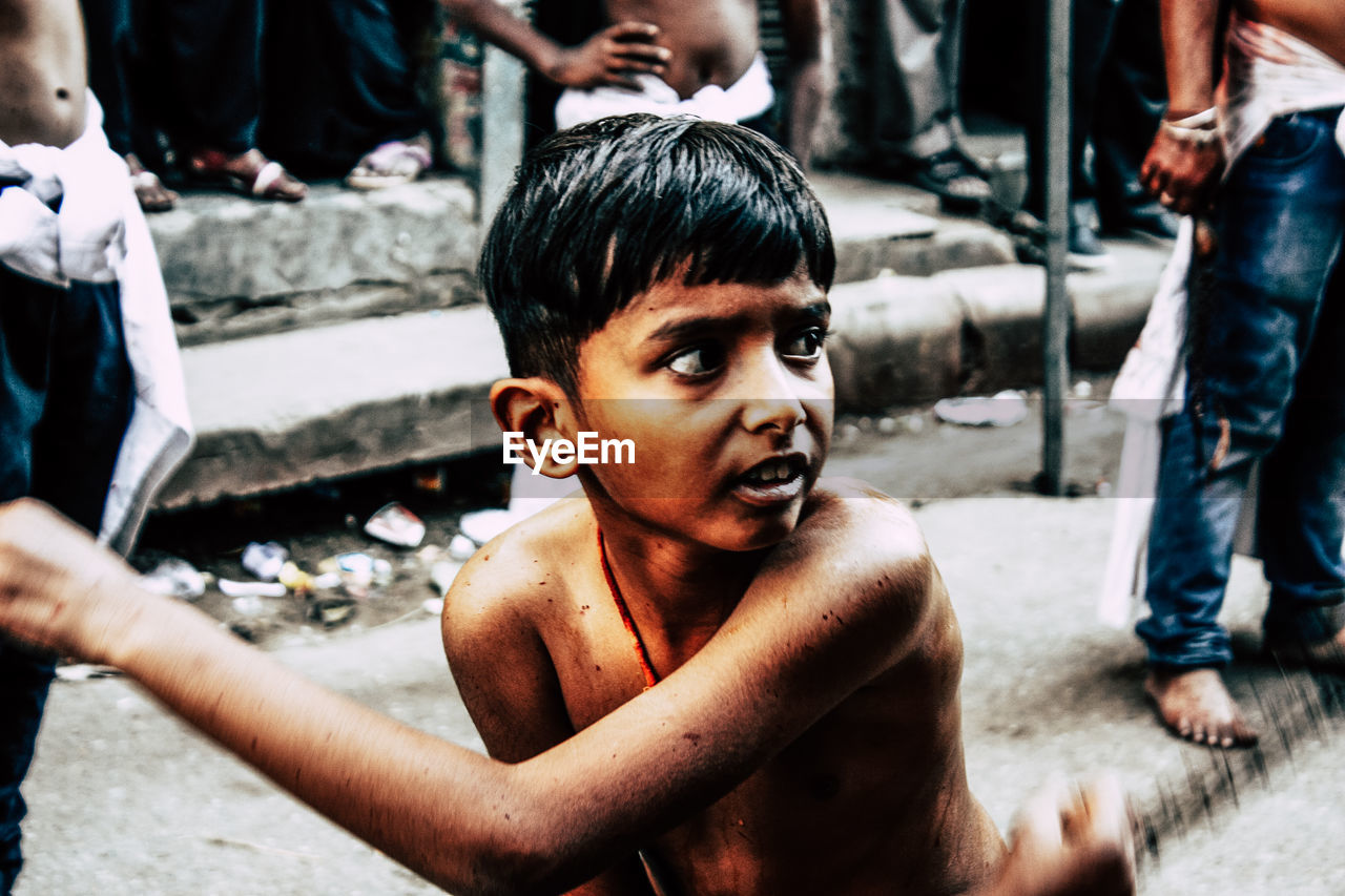 PORTRAIT OF SHIRTLESS BOY WITH MAN ON STREET