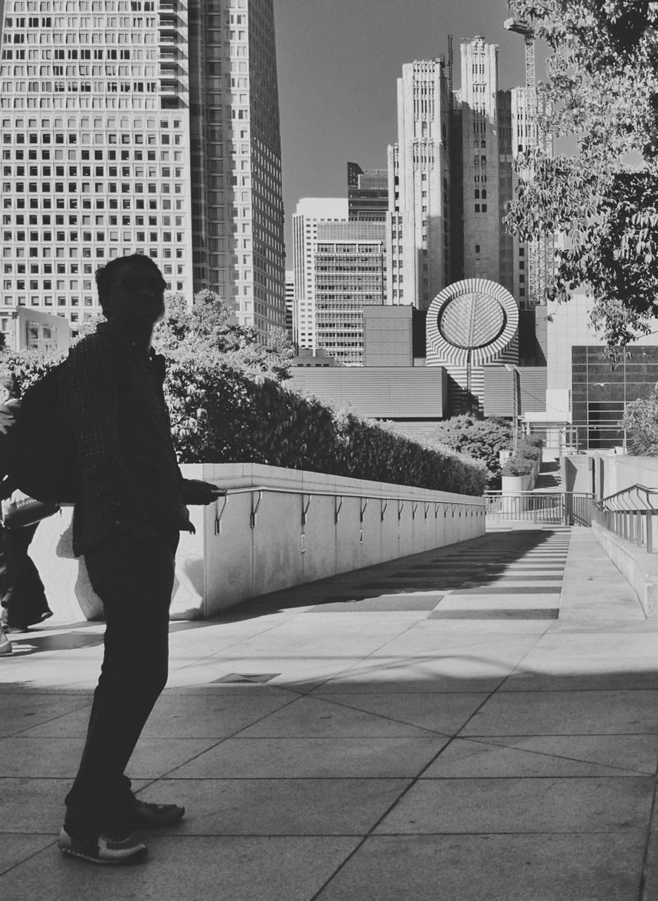 Full length of man standing on footpath against city buildings