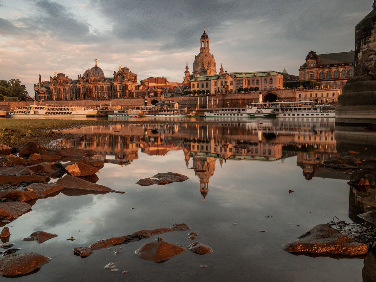 Reflection of buildings in puddle against sky