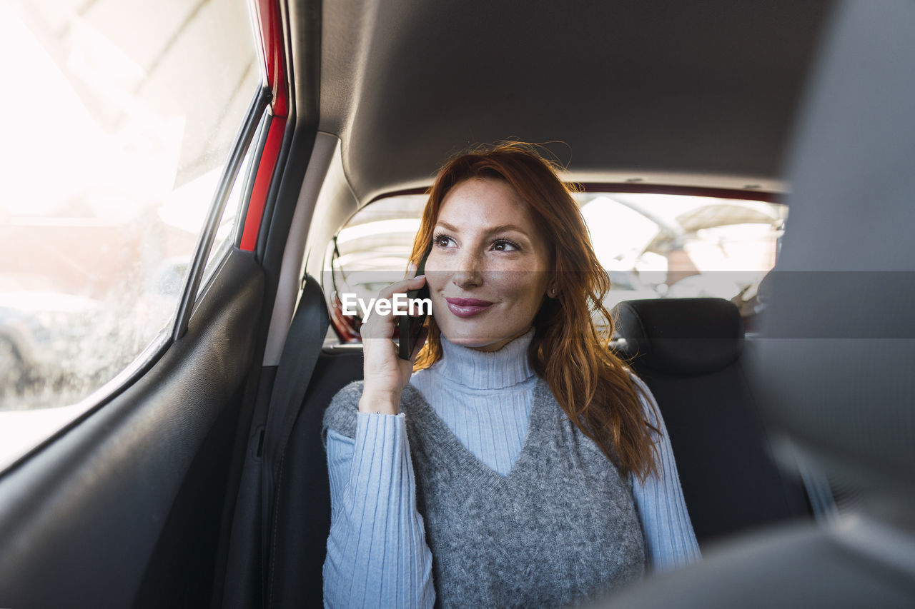 Smiling woman talking on smart phone in car