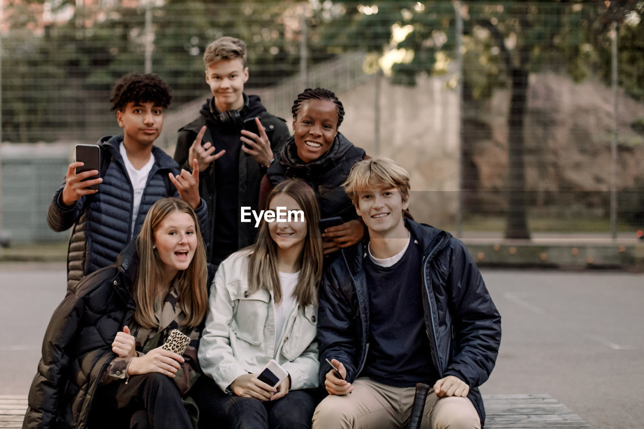 Portrait of smiling multi-ethnic male and female teenage friends at park in city