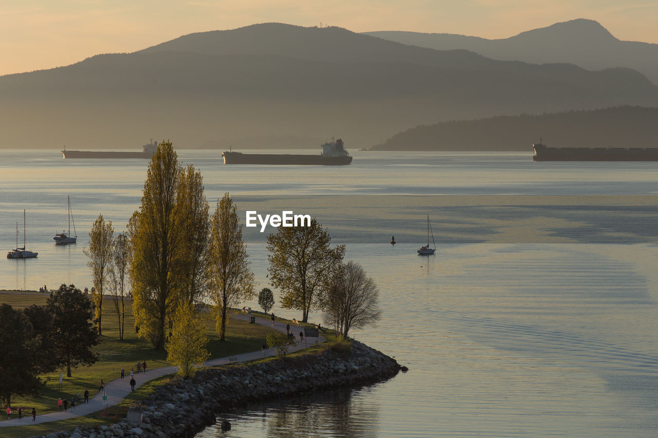 Scenic view of english bay by mountains during sunset