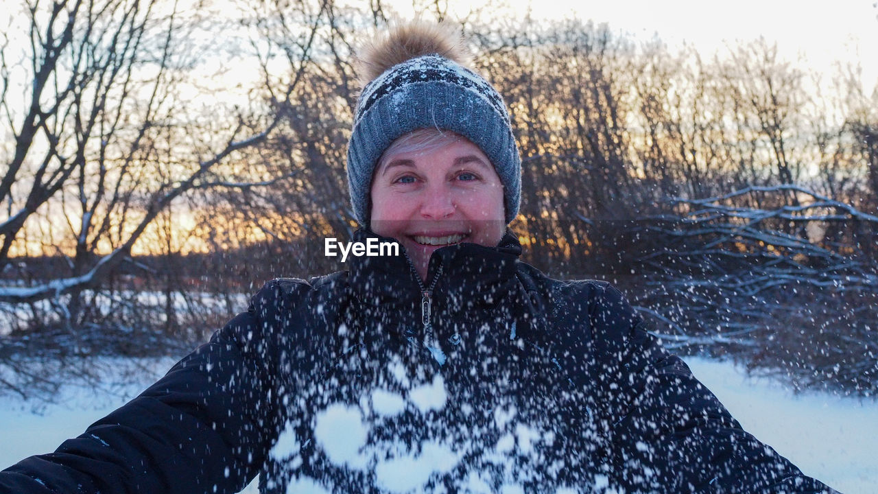 Portrait of woman in snow against trees during winter